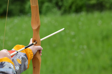 Boy aiming home-made wooden bow outdoors