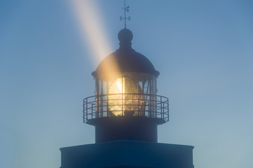 Lighthouse tower in the night with strong light beam