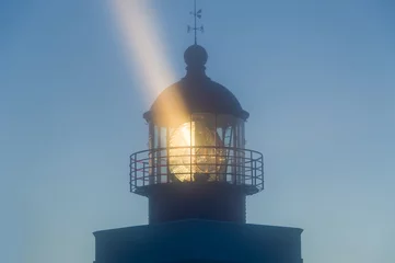 Meubelstickers Vuurtoren Lighthouse tower in the night with strong light beam