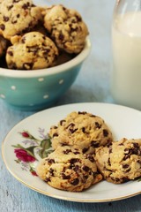 Homemade Chocolate chip cookies on floral plate and milk bottle on side, selective focus