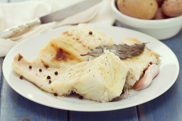 boiled cod fish on white plate and boiled potato in bowl