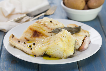 boiled cod fish with black pepper on white plate and boiled potato in bowl