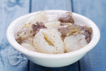 squids in white plate on blue wooden background