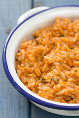 rice with seafood in dish with glass of white wine on blue wooden background