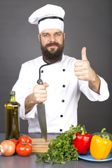 Happy chef holding a big sharp knife and showing thumb up ready