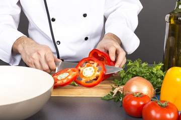 Chef's hands cutting red fresh pepper