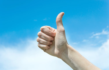 The hand shows OK against the sky