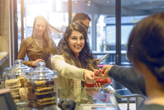 Junge Frau bezahlt an der Kasse eines Bistros