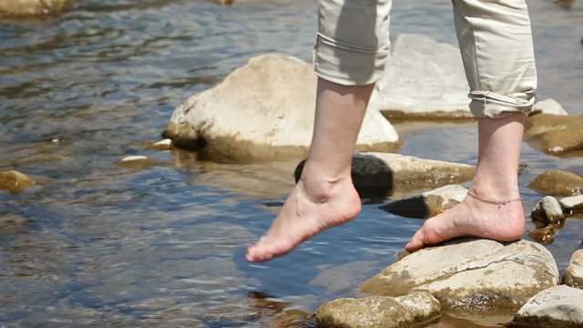 Barefoot female try cold water in mountain river