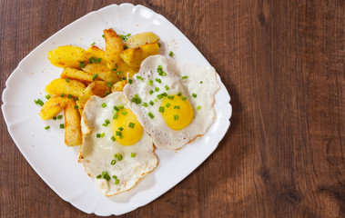 fried eggs with potato in a plate on wooden table