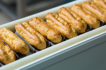 Yellow eclair shells. Narrow conveyor line with eclairs. Quality over quantity. Product that sells well.