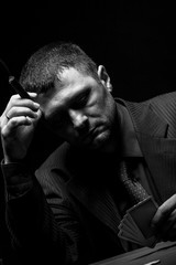 Male gambler playing poker, drinking whiskey and smokes a cigar, Black and white