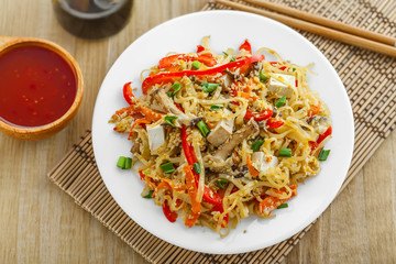 Plate of traditional Asian food on a table. Rice noodles with tofu, vegetables and shiitake mushrooms. Oriental cuisine meal. Top view.