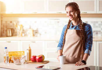 Positive woman standing  in the kitchen.