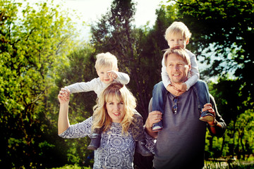 Happy kids sitting on pearents shoulder.