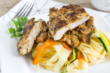 Roasted chicken with pasta and colorful vegetables