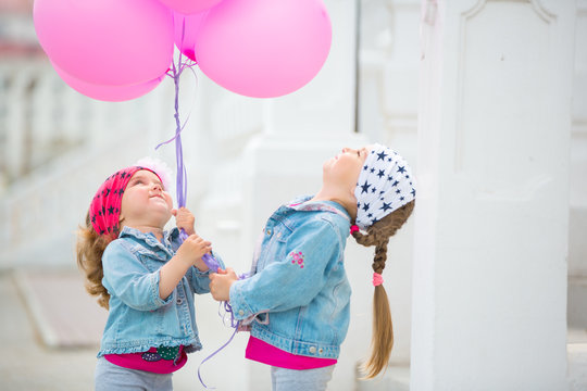 Happy little girls with pink balloons .
