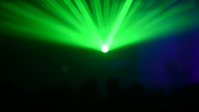 Unrecognizable people watching a beautiful laser show with multicolored lights
