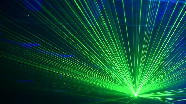 Unrecognizable people watching a beautiful laser show with multicolored lights