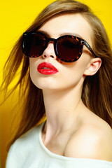 Portrait of a beautiful girl in glasses on a yellow background in the studio