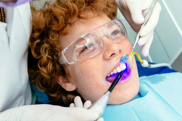 The doctor inspects the baby teeth using a UV lamp