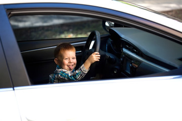 Cute little boy driving fathers car