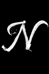 Letter N made of milk, isolated on black