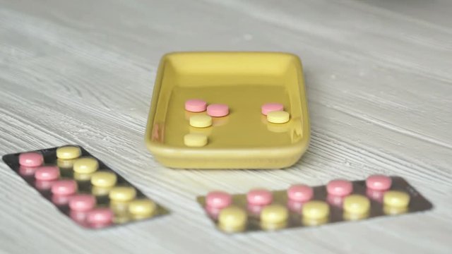 Hand takes pills in container placed on the table