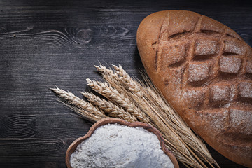 Baked bread golden wheat rye ears wooden bowl with flour on wood