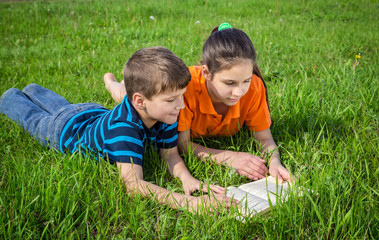 Two kids on green meadow with book