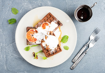 Belgian soft waffles with blood orange, cream, marple syrup and mint  on white plates 