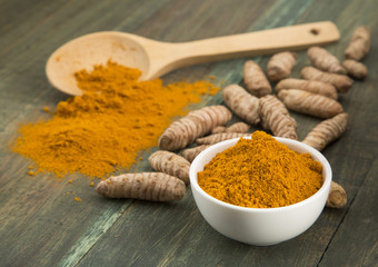 turmeric powder in white bowl on wooden background