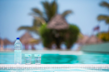 Glasses of waters and bottle background swiming pool