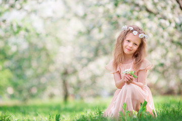 Fototapeta na wymiar Little girl in blooming cherry tree garden outdoors