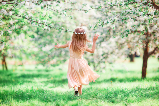 Adorable little girl in blooming cherry tree garden outdoors