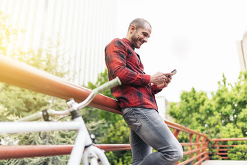 Young man with mobile phone and fixed gear bicycle.