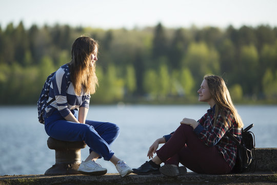 Two Friends Teen Girls Spend Time Together At The Pier Of The River.