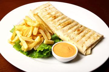 Pita with fries and sauce on a plate