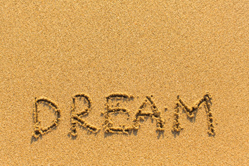 Dream - word drawn on the golden sand sea beach.