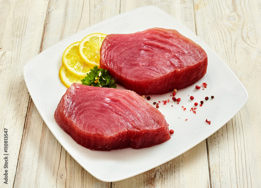 Wall mural raw tuna steaks with lemon, herbs and peppercorns