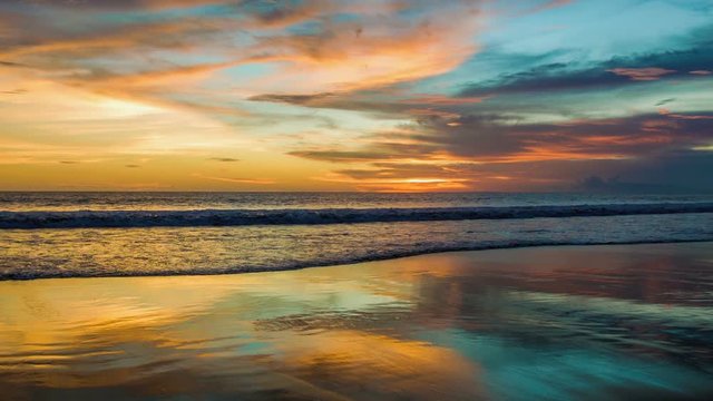 Colorful sunset at ocean with reflections on sand
