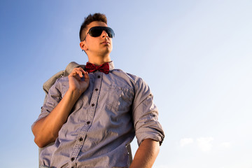 outdoor fashion lifestyle image, young handsome man looking to sky in sunglasses