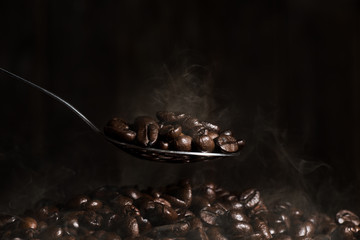 Scooping hot coffee beans with spoon.