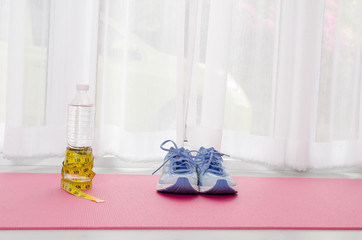 Sport shoes, yoga mat, bottle of water and centimeter on wooden