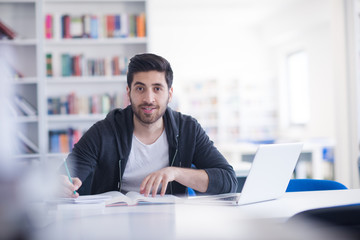 student in school library using laptop for research