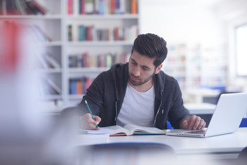 student in school library using laptop for research