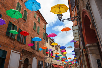 Colorful umbrellas hanging above street of Ferrara, Italy