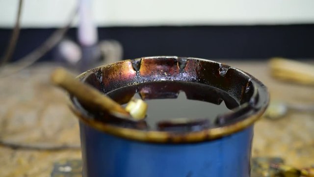 Using pen-like tool used to apply liquid hot wax n the batik-making process.