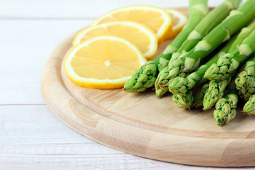 fresh  asparagus sliced lemon on a wooden cutting Board on white wooden background