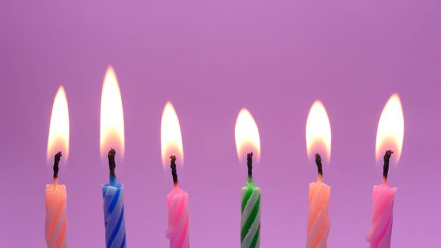 Burning birthday candles on pink background